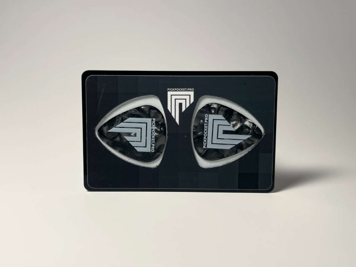 A dark-colored PickPocketPro Card with a geometric design, featuring two standard-size guitar picks on the front side.